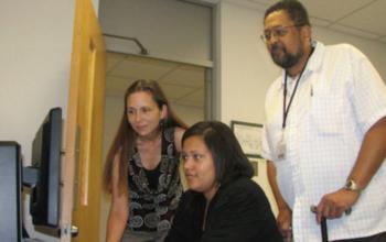 three people looking at computer