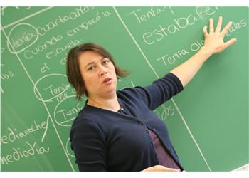 teacher pointing to chalkboard with spanish text