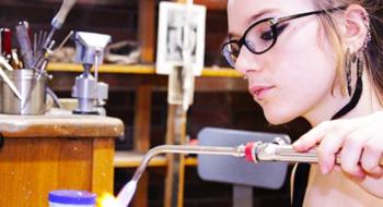 student with a torch in jewelry class