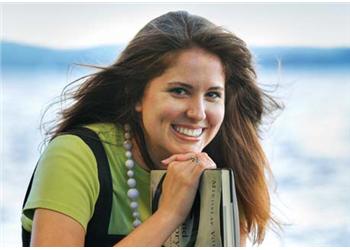 smiling woman holding books near water