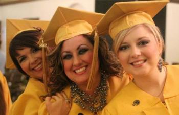 three graduates smiling in caps and gowns