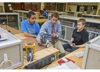 three people with a robot in a lab setting