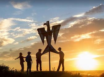 silhouettes by a sculpture at sunset