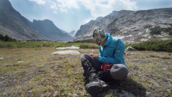 person sitting in a mountain landscape with gear