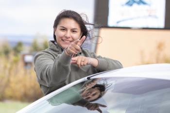 student making a peace sign by a car