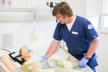 student in nursing uniform practicing on a mannequin