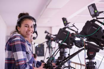 student operating video cameras with headset on