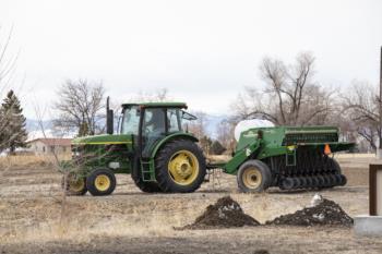 tractor pulling a seeder in a bare field