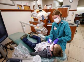 dental hygiene student with patient in clinic