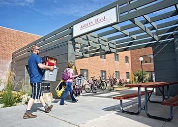 students walking by 'ashley hall' with gear