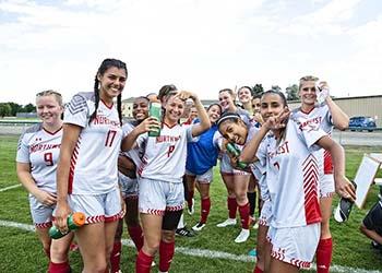 soccer team posing with thumbs up on field