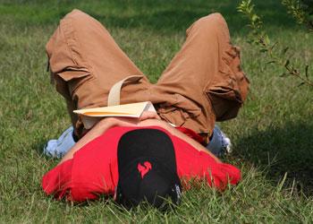 student lying on grass with book