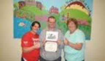 three people holding certificate in front of a colorful mural