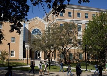 students passing by a grand building with large windows