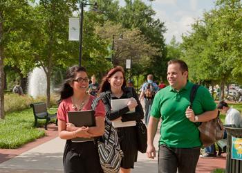 three people with backpacks walking and conversing outdoors