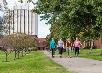 students walking on campus pathway by modern building