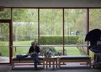 person sitting by a window with a book in a lounge area