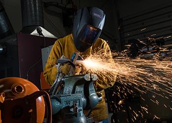 student welding with sparks flying in workshop