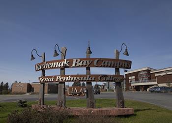 sign 'kenai peninsula college' with building behind